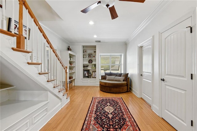 living area with ceiling fan, light wood-type flooring, and ornamental molding