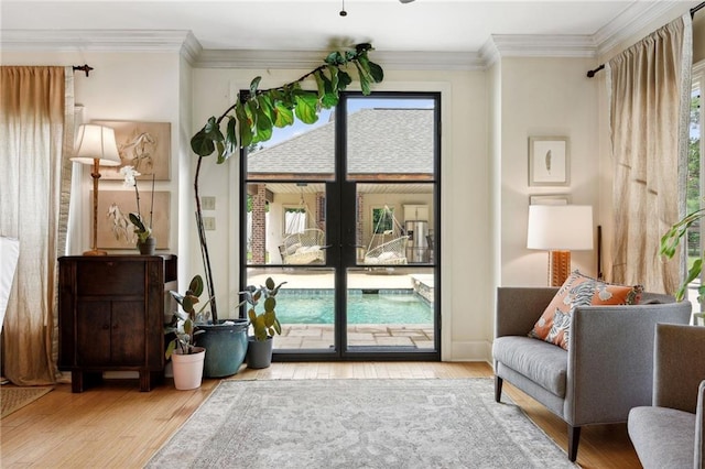 sitting room with a wealth of natural light, ornamental molding, and light hardwood / wood-style flooring