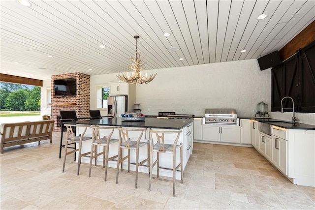 kitchen with hanging light fixtures, stainless steel refrigerator with ice dispenser, white cabinetry, and a breakfast bar