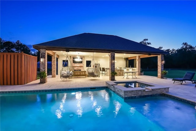 pool at dusk with a patio and an in ground hot tub