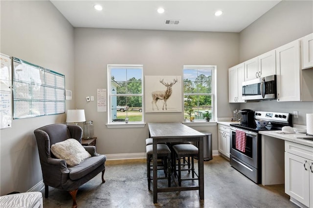 kitchen with a wealth of natural light, white cabinetry, and appliances with stainless steel finishes