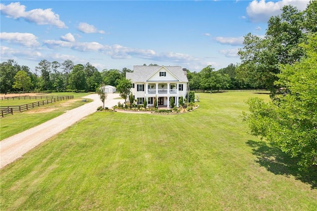 view of front facade with covered porch, a rural view, and a front yard