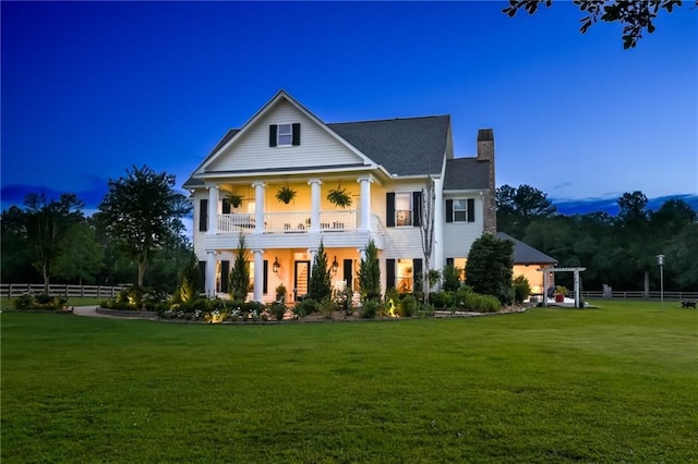 greek revival house featuring a balcony and a lawn