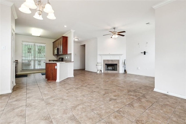 kitchen featuring pendant lighting, ceiling fan with notable chandelier, a tiled fireplace, and crown molding