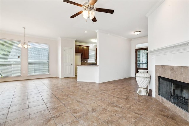 unfurnished living room featuring ceiling fan with notable chandelier, light tile patterned floors, ornamental molding, and a fireplace