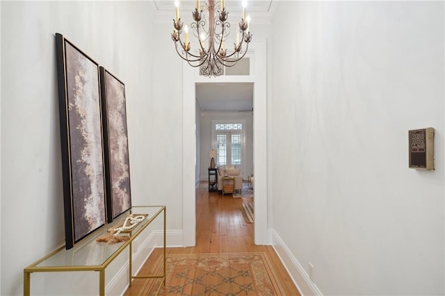 hallway with a chandelier, hardwood / wood-style floors, and ornamental molding