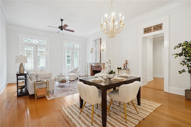 dining space with ceiling fan with notable chandelier, light hardwood / wood-style floors, and crown molding