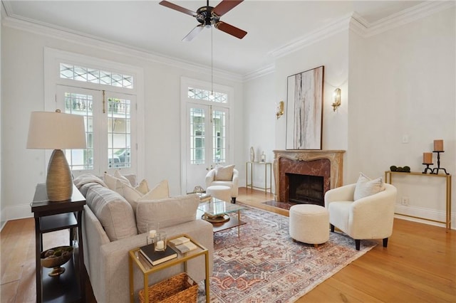 living area featuring a fireplace, wood-type flooring, ceiling fan, and crown molding