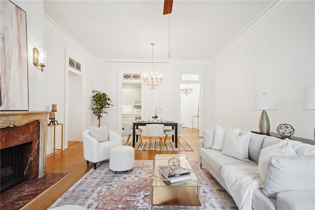 living room featuring a chandelier, a fireplace, hardwood / wood-style flooring, and crown molding