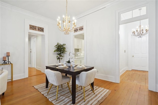 dining space with a chandelier, light wood-type flooring, and ornamental molding