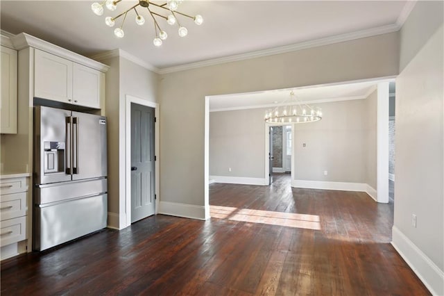 interior space with baseboards, a notable chandelier, dark wood-style floors, and ornamental molding