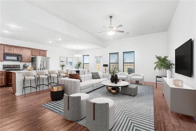 living room with ceiling fan with notable chandelier and dark hardwood / wood-style flooring