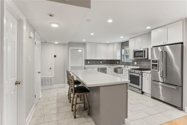 kitchen featuring light stone countertops, a breakfast bar area, a center island, white cabinets, and premium appliances