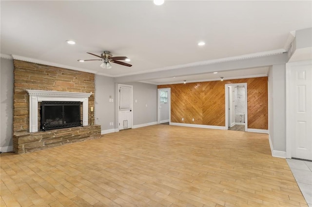 unfurnished living room featuring a stone fireplace, light hardwood / wood-style flooring, and wood walls