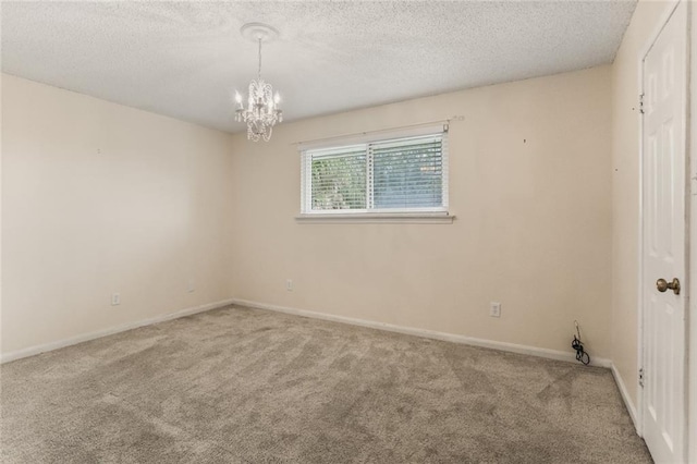 carpeted spare room with a textured ceiling and a notable chandelier