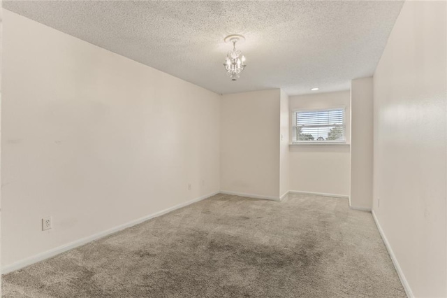 unfurnished room with a textured ceiling, light carpet, and a notable chandelier