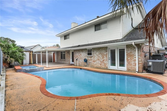 view of pool with a patio area, cooling unit, and an in ground hot tub