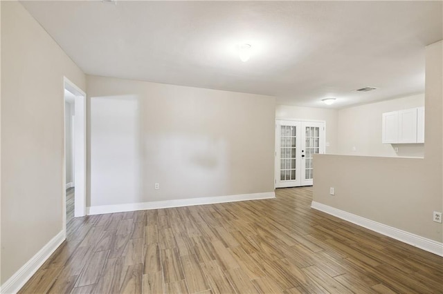 unfurnished room featuring french doors and light hardwood / wood-style flooring