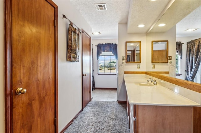 bathroom with vanity, a textured ceiling, and tile patterned flooring