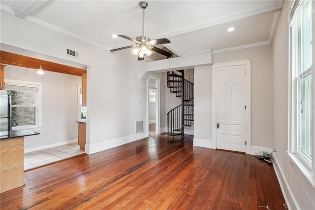 unfurnished living room with a wealth of natural light, hardwood / wood-style flooring, ceiling fan, and beam ceiling