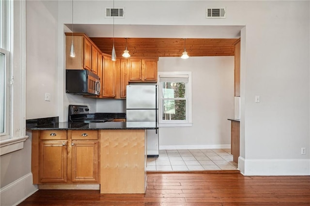 kitchen featuring pendant lighting, light wood-type flooring, appliances with stainless steel finishes, and dark stone countertops