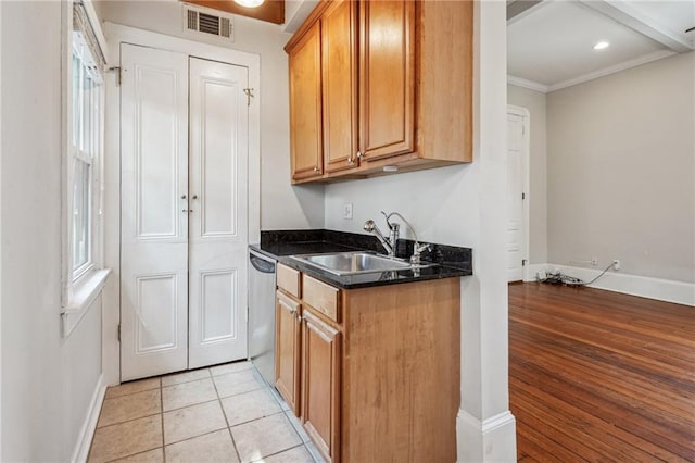 kitchen featuring ornamental molding, dark stone counters, sink, stainless steel dishwasher, and light hardwood / wood-style flooring