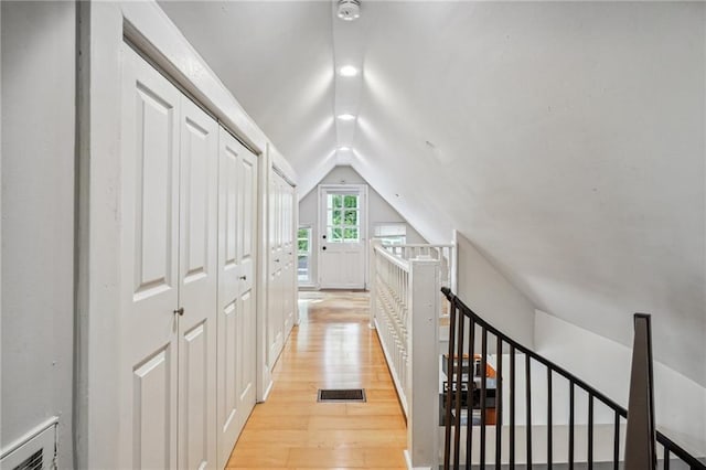 hallway with light wood-type flooring and vaulted ceiling