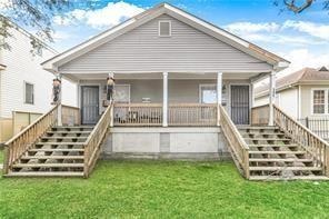 rear view of property with a porch and a lawn