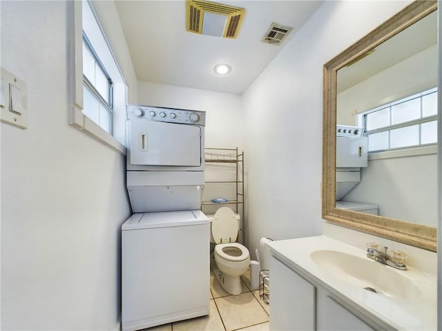 bathroom with tile patterned floors, a healthy amount of sunlight, stacked washer / drying machine, and toilet