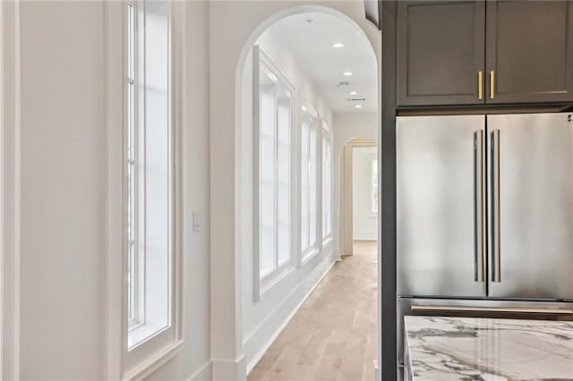 kitchen with high end fridge, light stone countertops, and light hardwood / wood-style floors