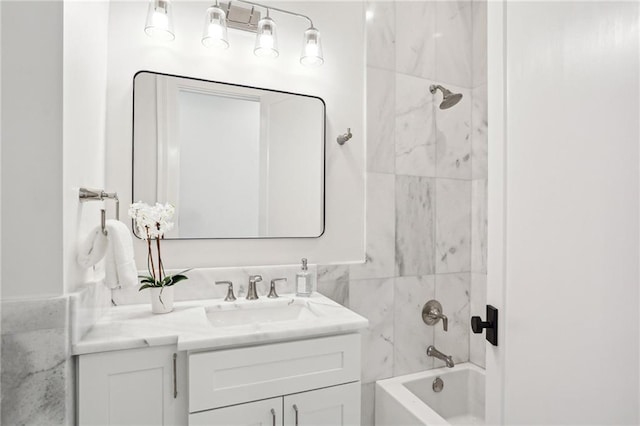 bathroom with tiled shower / bath combo, vanity, and tile walls