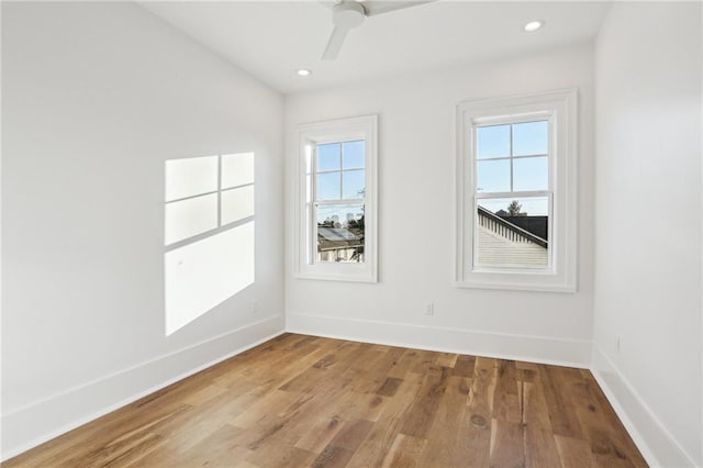 empty room with a healthy amount of sunlight, ceiling fan, and light hardwood / wood-style flooring