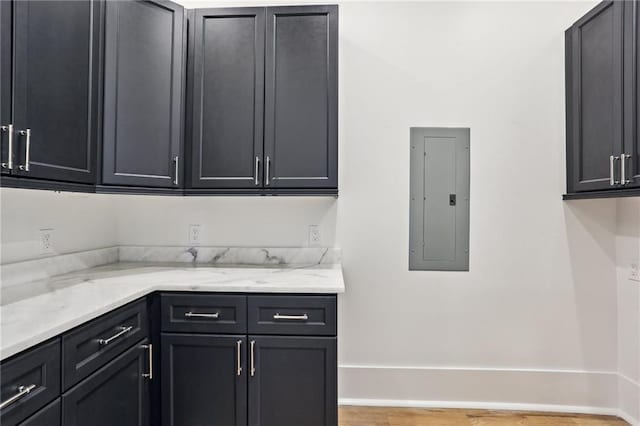 kitchen featuring electric panel and light stone countertops