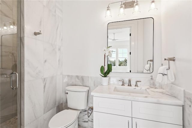 bathroom with vanity, toilet, a shower with shower door, and tile walls