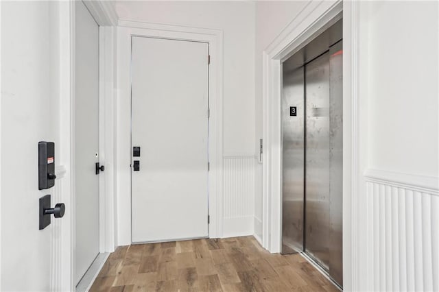 doorway with light hardwood / wood-style floors and elevator