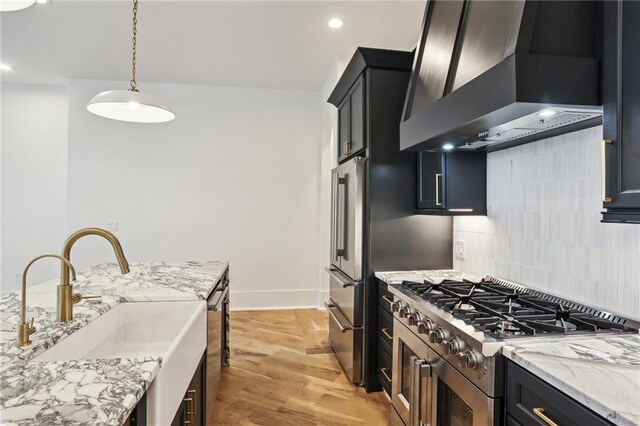 2435 Napoleon Ave Unit 2A, New Orleans, LA 70115 - kitchen featuring stainless steel refrigerator, premium range hood, decorative light fixtures, a kitchen island with sink, and light wood-type flooring