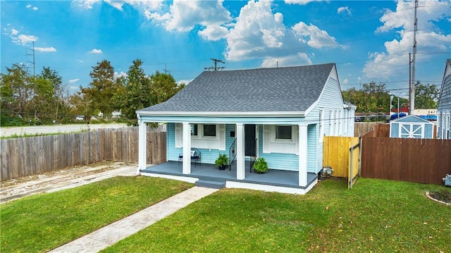 rear view of house featuring a storage unit, a lawn, and covered porch