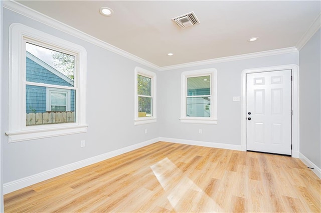 empty room with plenty of natural light, light hardwood / wood-style floors, and crown molding