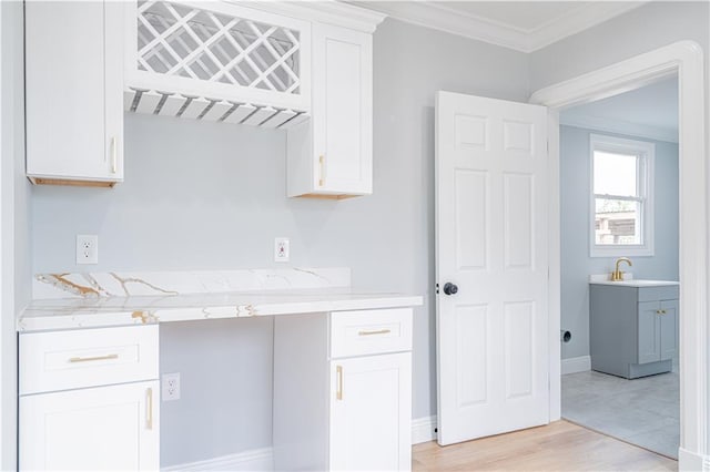 kitchen with light wood-type flooring, white cabinetry, sink, and crown molding