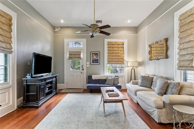 living room featuring a wealth of natural light, wood-type flooring, and ceiling fan