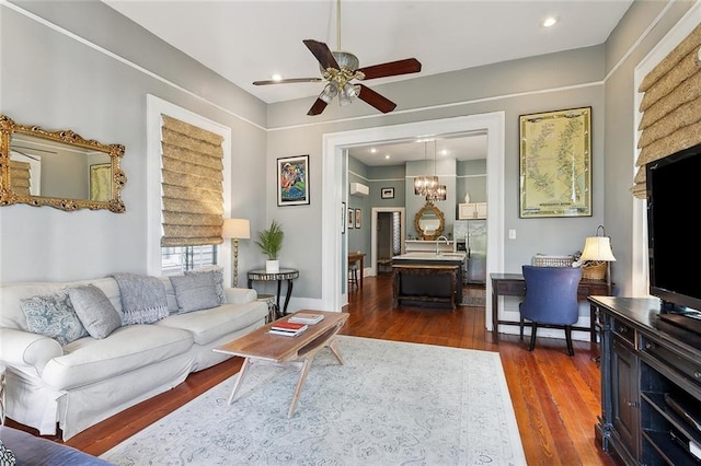 living room featuring dark wood-type flooring and ceiling fan with notable chandelier