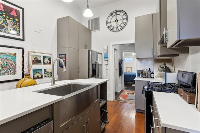 kitchen with dark wood-type flooring, decorative backsplash, black range with gas cooktop, gray cabinets, and pendant lighting