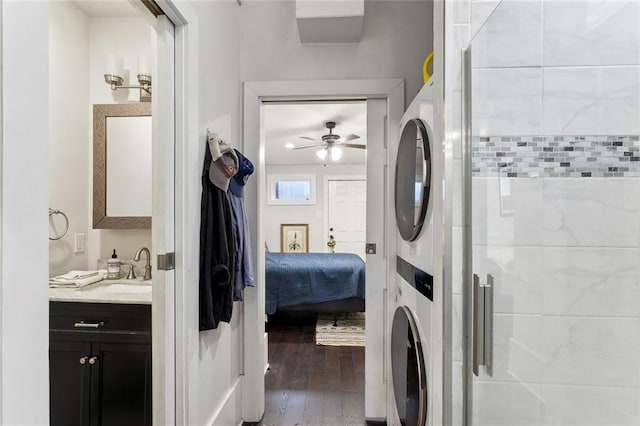 washroom with stacked washer and dryer, hardwood / wood-style flooring, sink, and ceiling fan