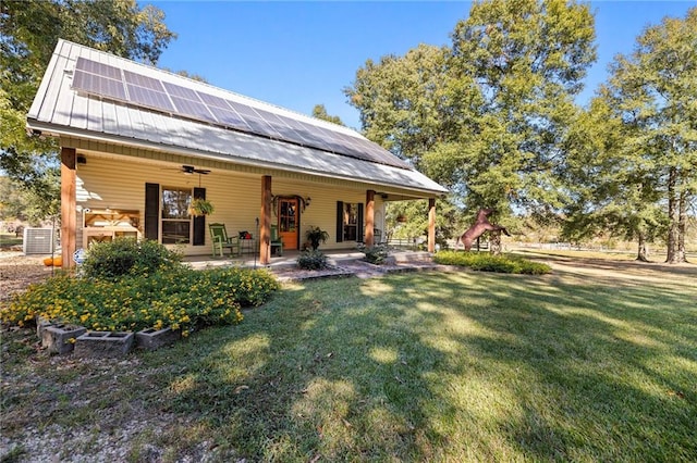 back of house featuring ceiling fan, solar panels, a yard, and a patio area