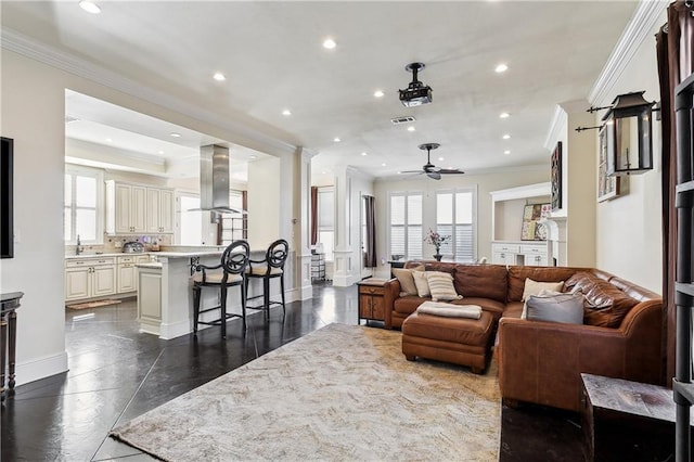 living room with ceiling fan, sink, and crown molding