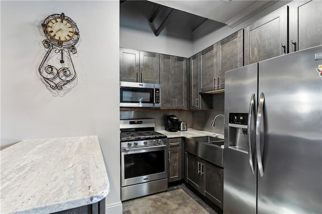 kitchen with light stone countertops, sink, appliances with stainless steel finishes, and dark brown cabinets