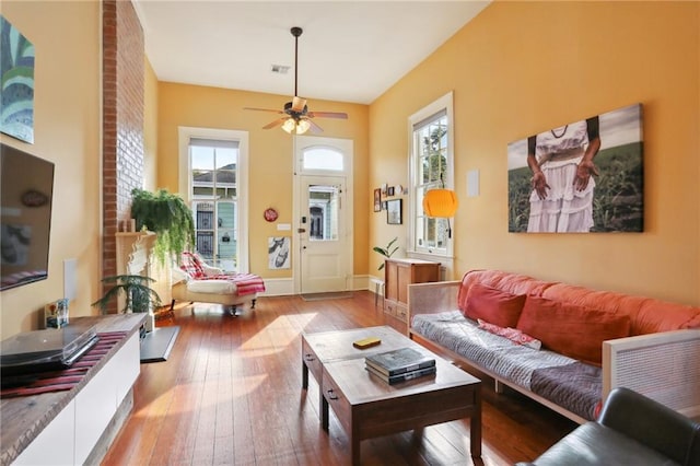 living room featuring ceiling fan, wood-type flooring, and a healthy amount of sunlight