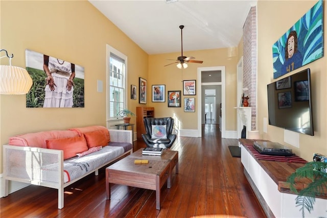 living room with dark wood-type flooring, ceiling fan, and a fireplace