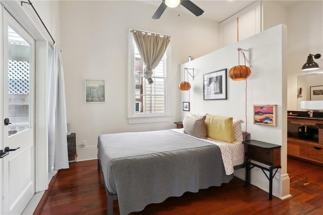 bedroom featuring multiple windows, dark hardwood / wood-style floors, and ceiling fan