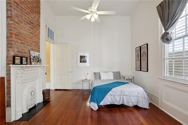 bedroom with ceiling fan, dark hardwood / wood-style floors, and a fireplace